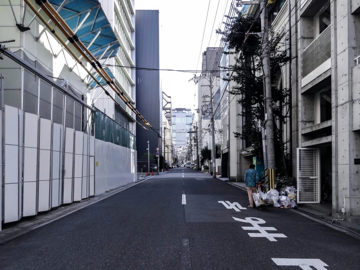 an empty street with many tall buildings and a man sitting on the side