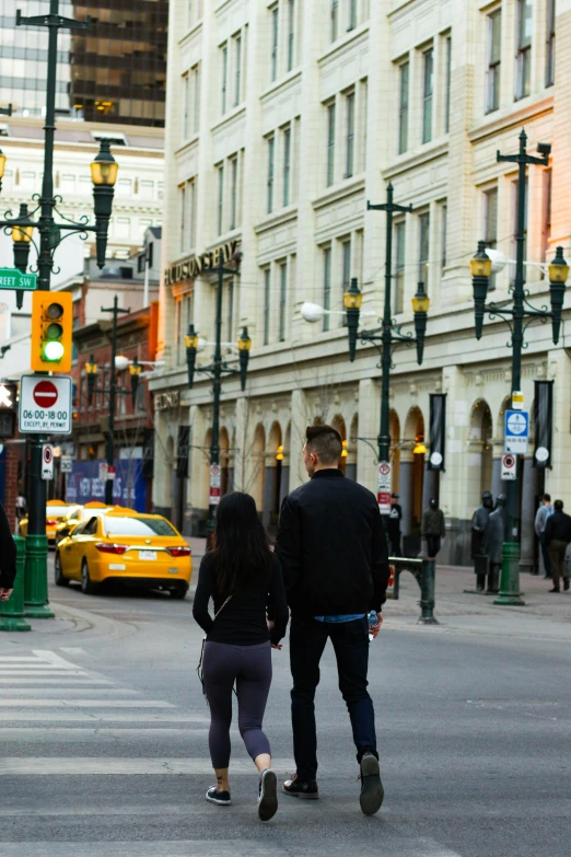 two people are walking across a busy street