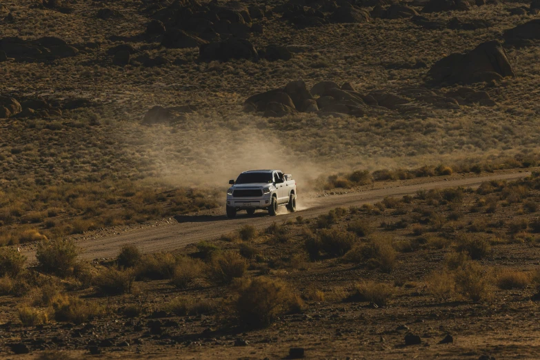 a white truck driving down the dirt road