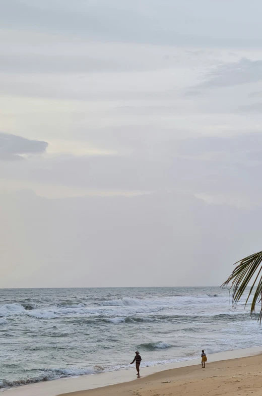 a beach scene with two people walking with a surfboard