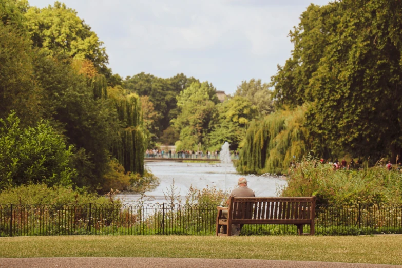 an elderly man sitting on a bench looking at the water