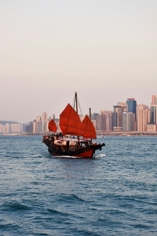 an orange chinese boat in front of a city