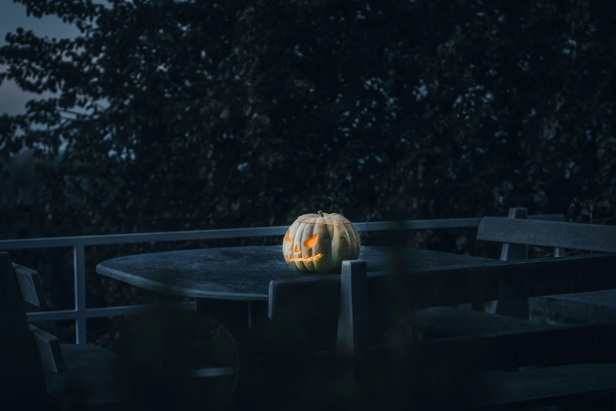 an illuminated pumpkin sitting on a table under the trees