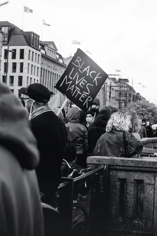 black lives matter protest sign and many people stand around