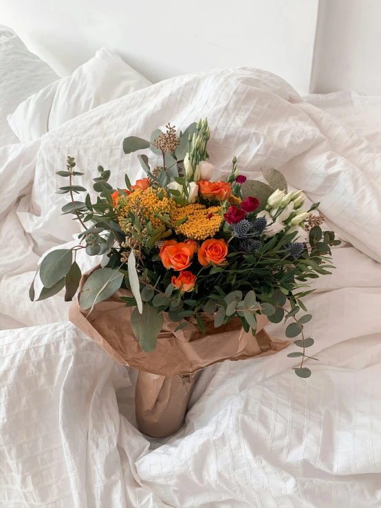 an arrangement of flowers sits on a white sheet