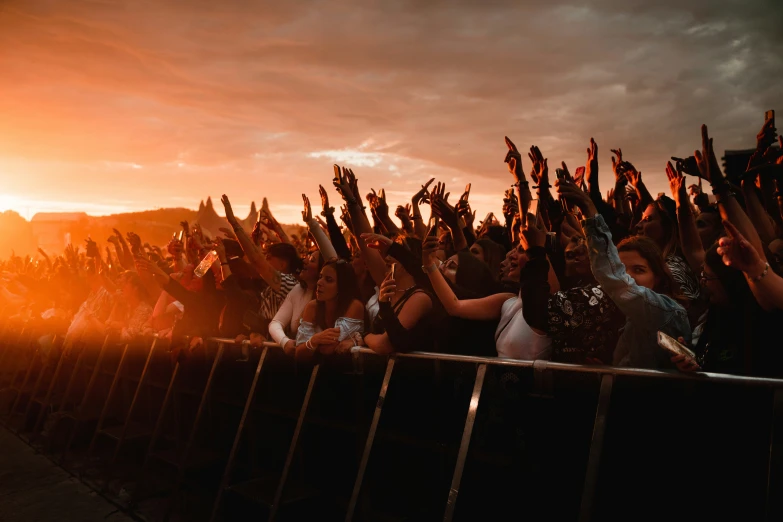 a crowd is behind a fence at sunset