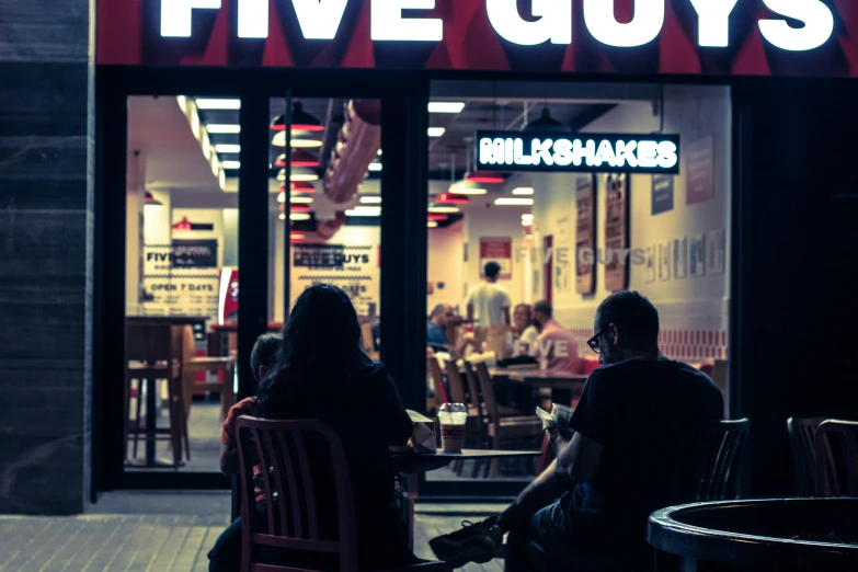 two people sitting in chairs outside a restaurant