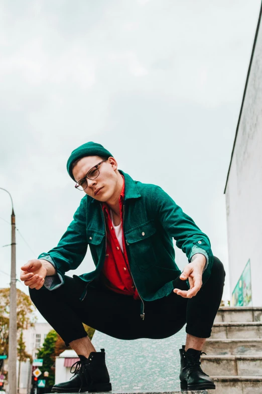 a man in black pants and green jacket kneeling on steps