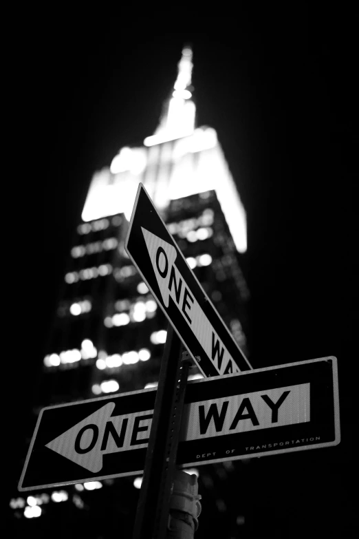 a one way sign in front of a building in the night