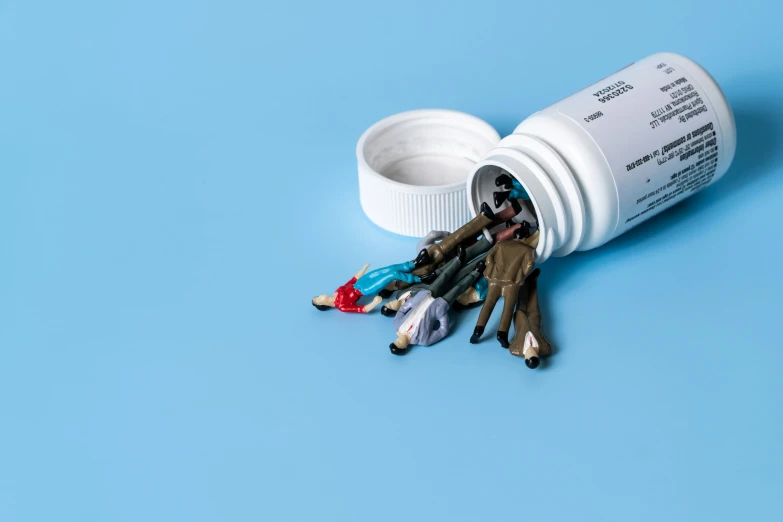 an open pill bottle laying on top of small wooden figures