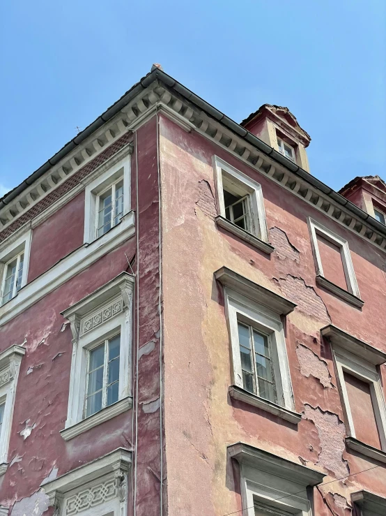 an old building with white window frames and a red paint over it