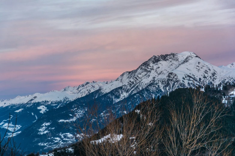 snowy mountains are in the background under a colorful sunset