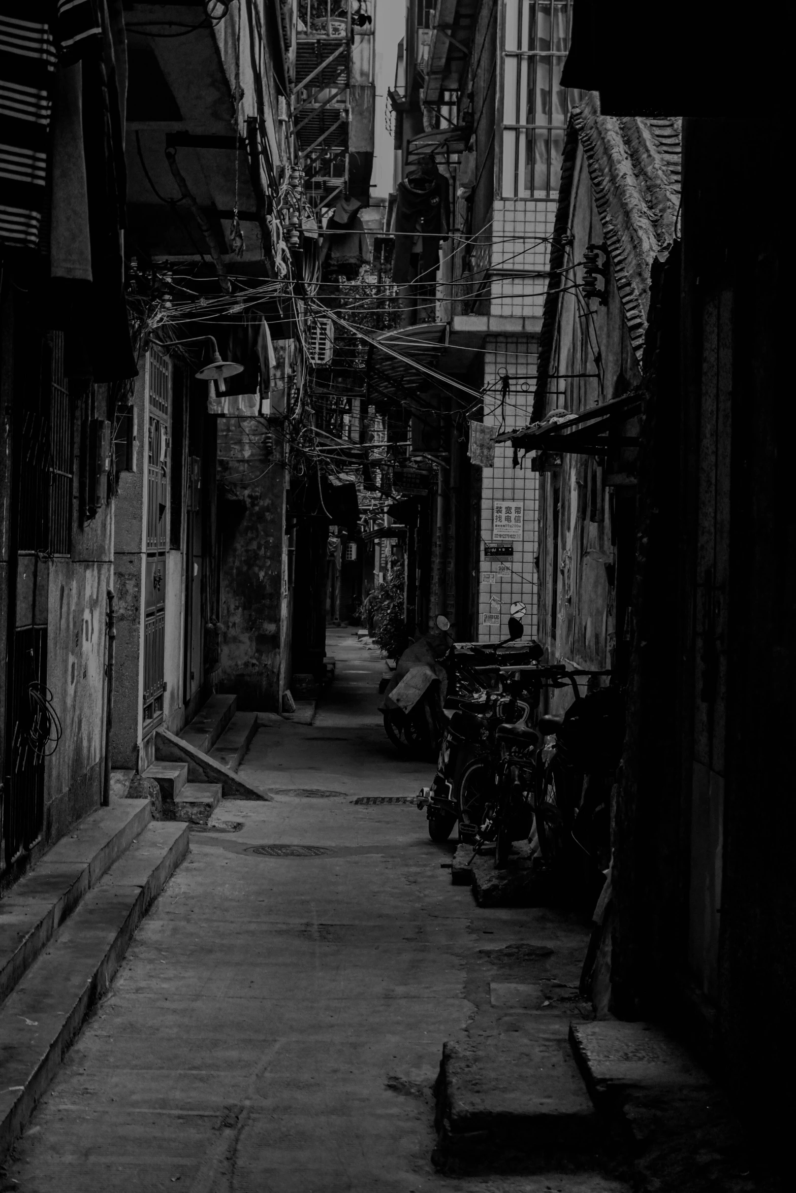 a long narrow, dark street with parked bicycles