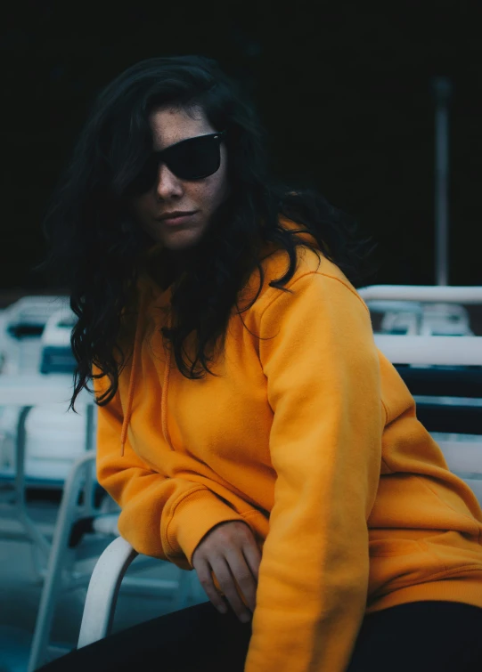 a woman sitting on top of a white chair wearing sunglasses