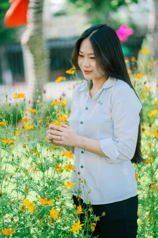 a woman in grey shirt and flower field next to trees