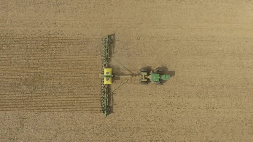 a tractor tilling the fields with a person using a thresher