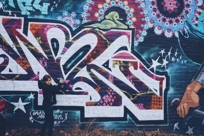 a person standing in front of a wall with graffiti