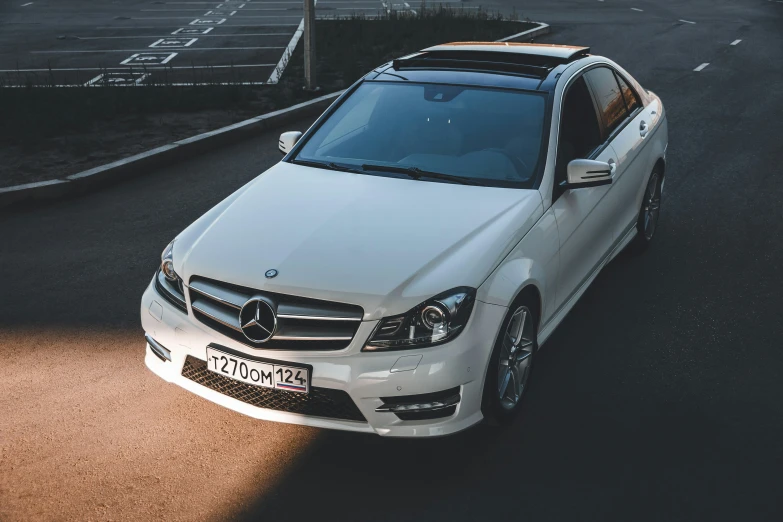 a white car sitting on top of a road next to a parking lot