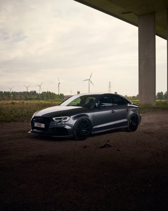 a black car is parked under a bridge