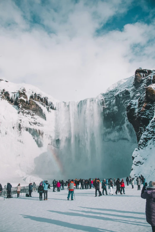 the people are standing around looking at the waterfall