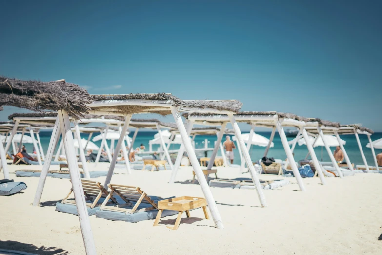 a group of chairs and straw umbrellas on a beach