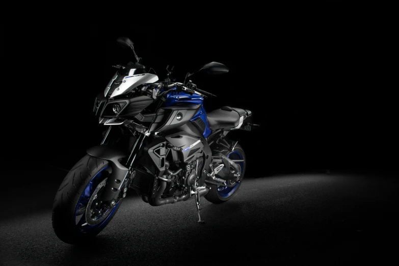 blue and silver motorcycle standing in a dark area