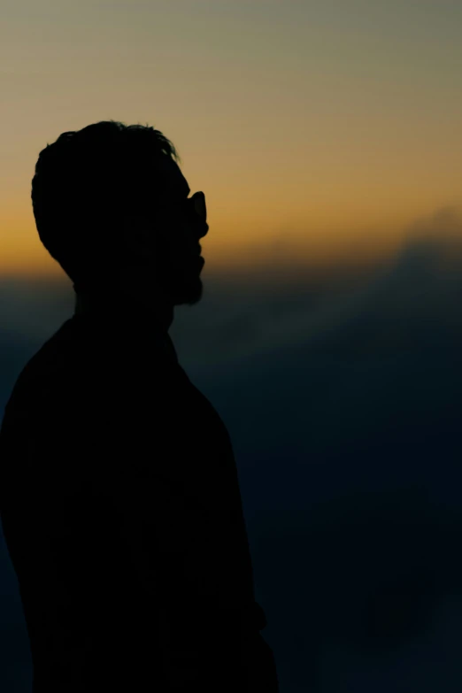 a man is standing in the dark during the sunset