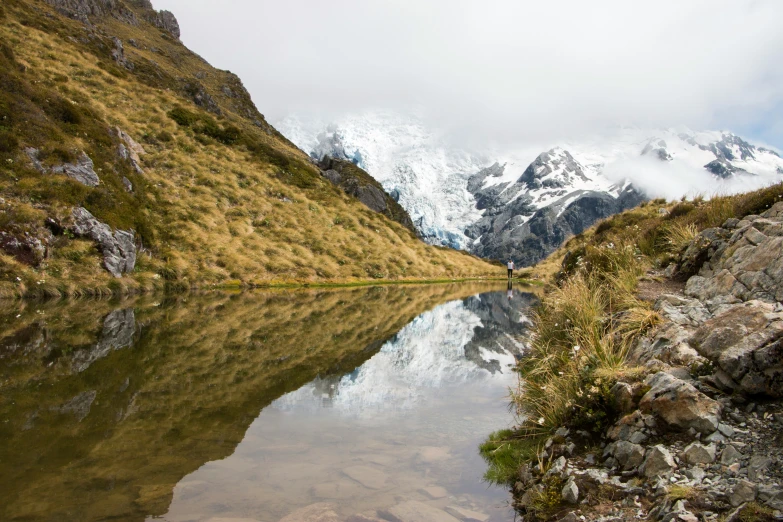 a clear pond with mountains in the background