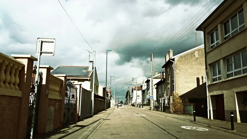 an empty street next to some buildings with clouds in the sky