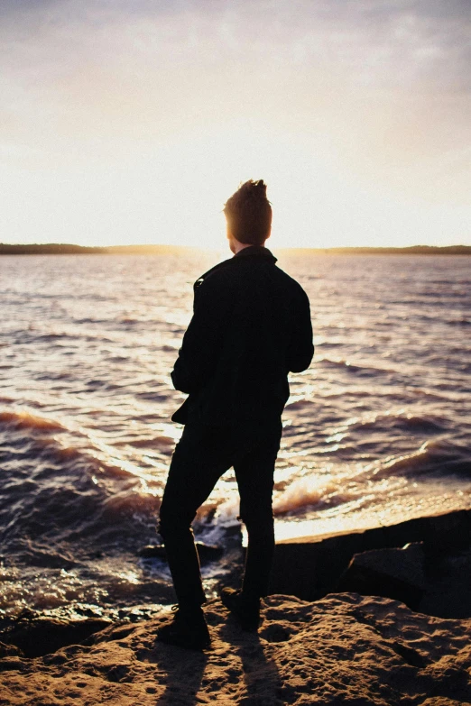 a person stands at the shore watching the water