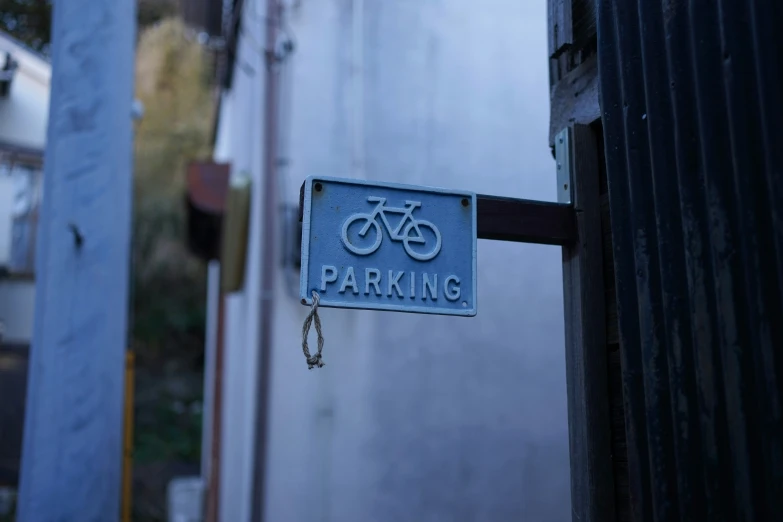 a blue bike parking sign with a chain attached to the back door