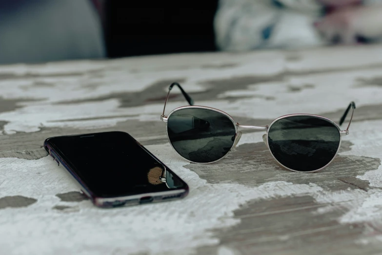 an iphone and sunglasses sitting on a surface