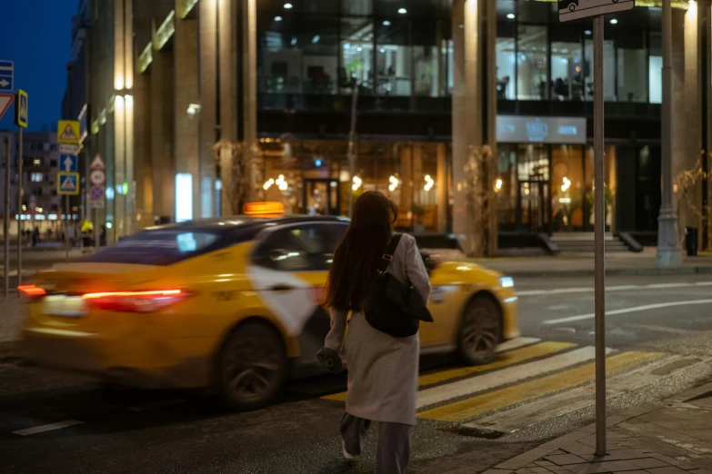 a woman walks down a city street at night