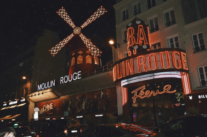 several buildings lit up with neon lights and a windmill
