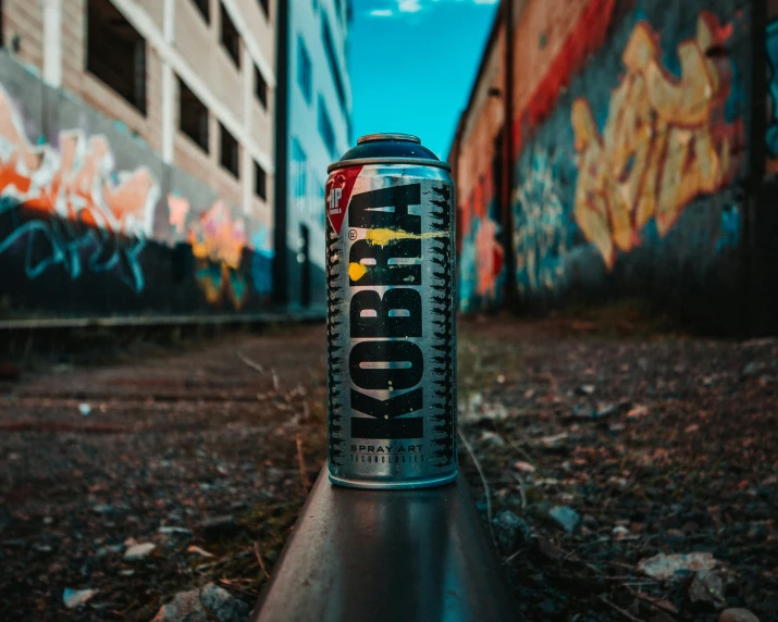 a can sitting next to a building and some graffiti