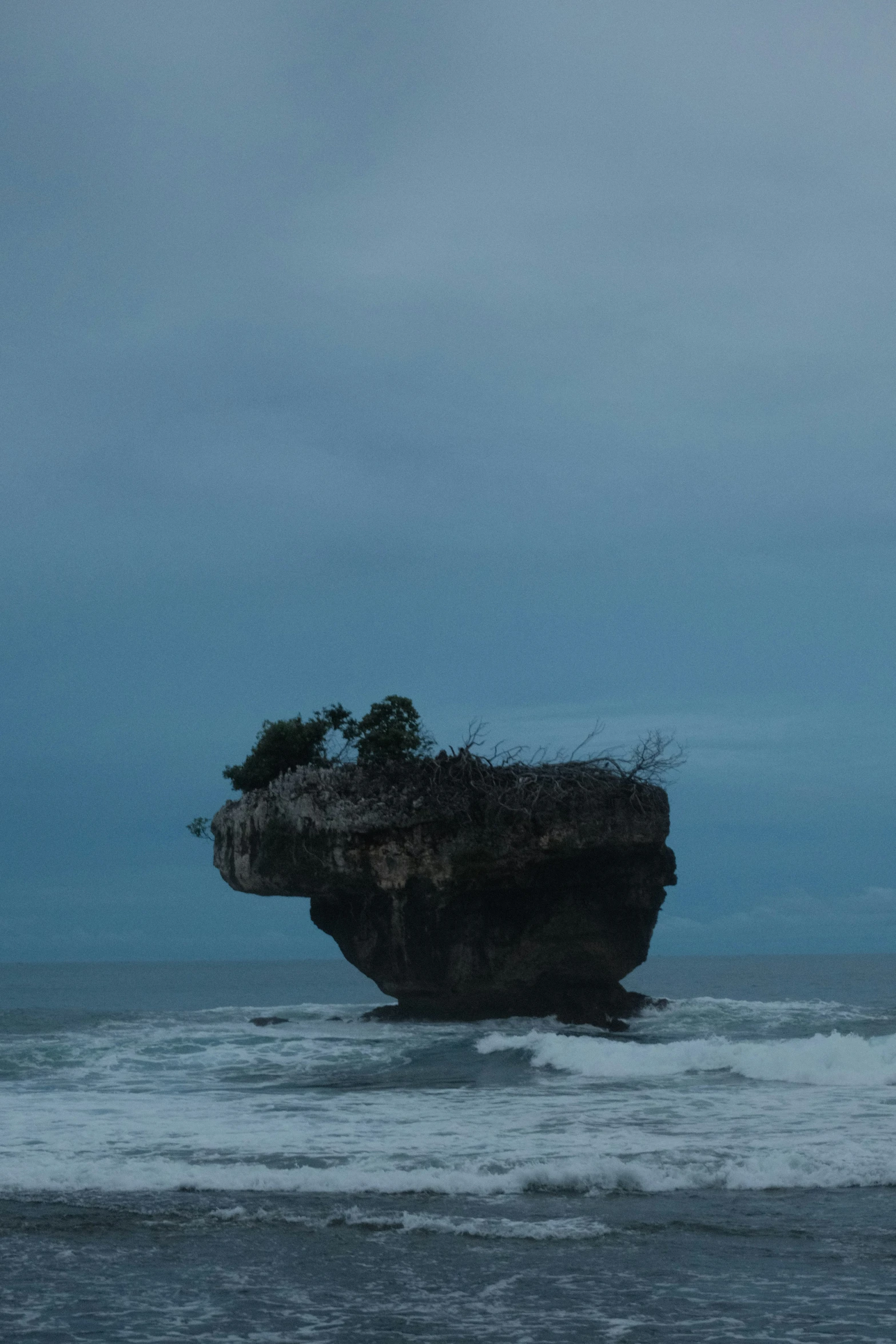 a person walking along a rocky shore towards an island