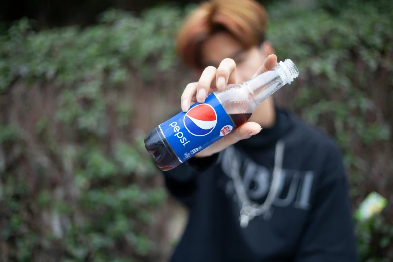 a young man is holding a pepsi cola bottle