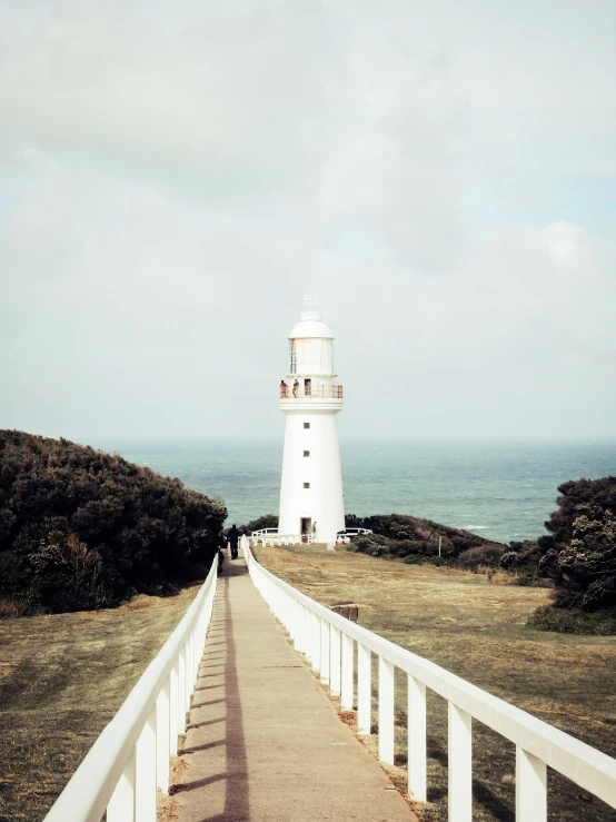 a lighthouse sitting on top of a hill near a bridge