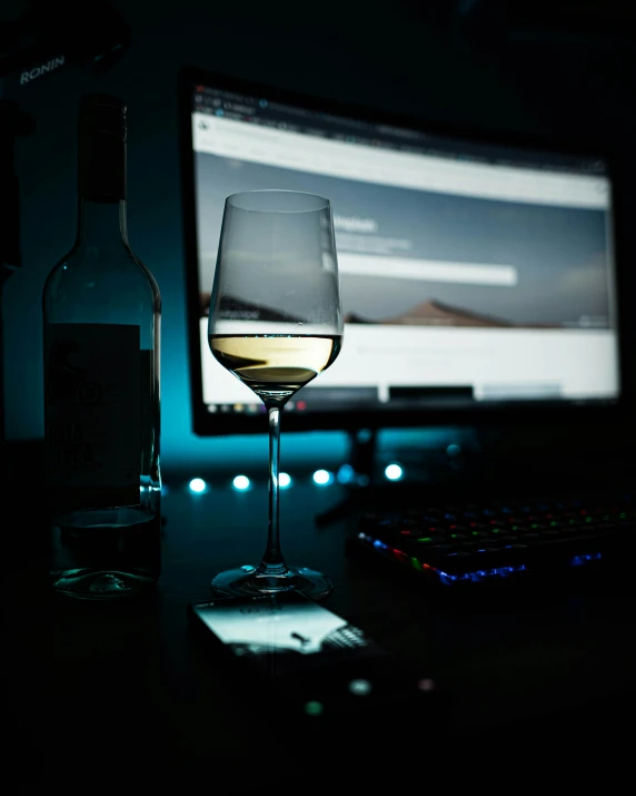 a dark room features a laptop and a wine glass