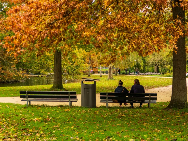 two people are sitting on the bench in the park