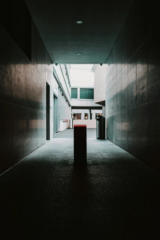 an empty hallway with red trash can in the middle