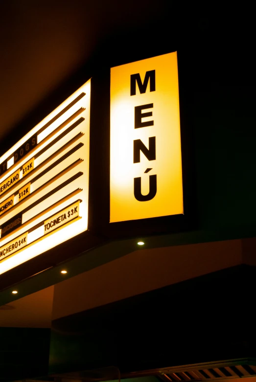 the menu on a sign is lit up at night