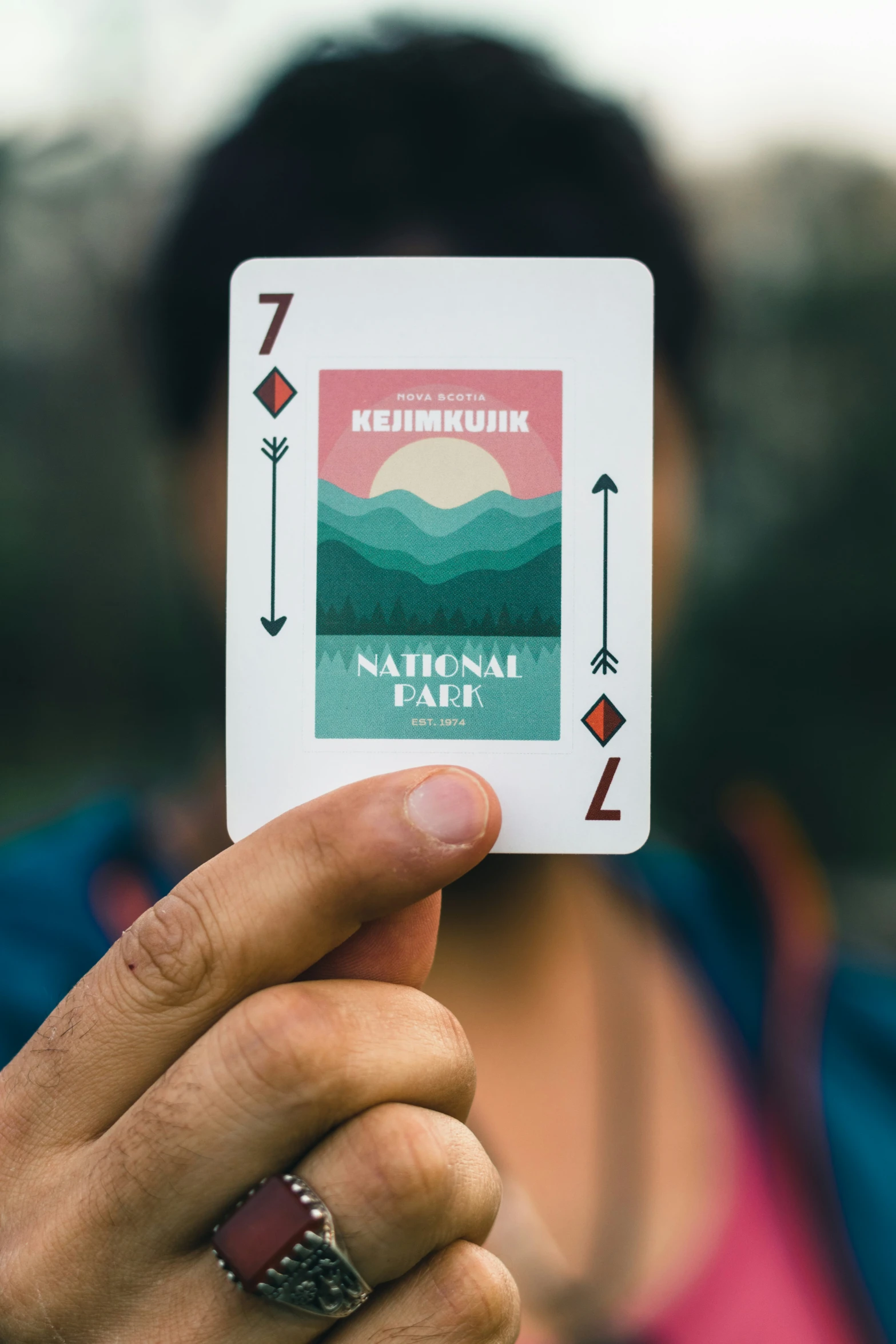 a person holding up a playing card with a mountain range on the back