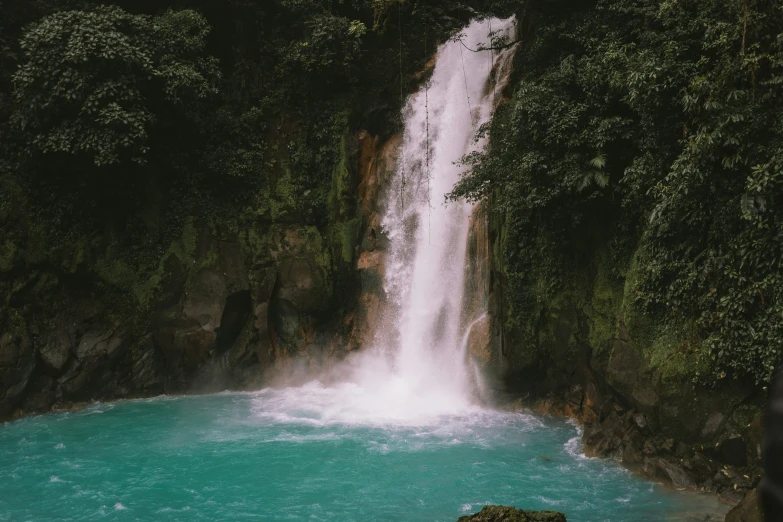 a small waterfall is near a blue pool