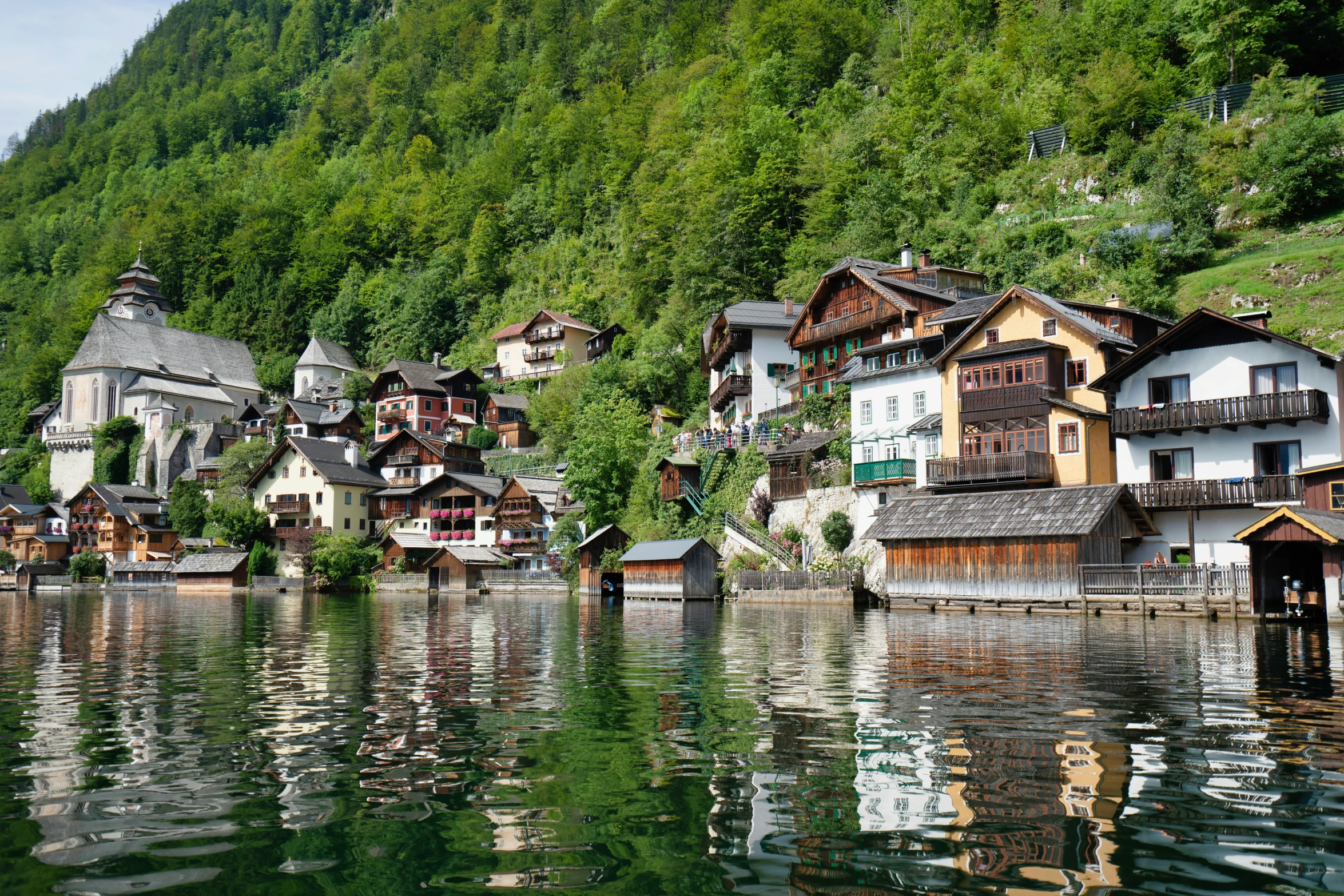 a row of wooden buildings on a hillside next to a body of water