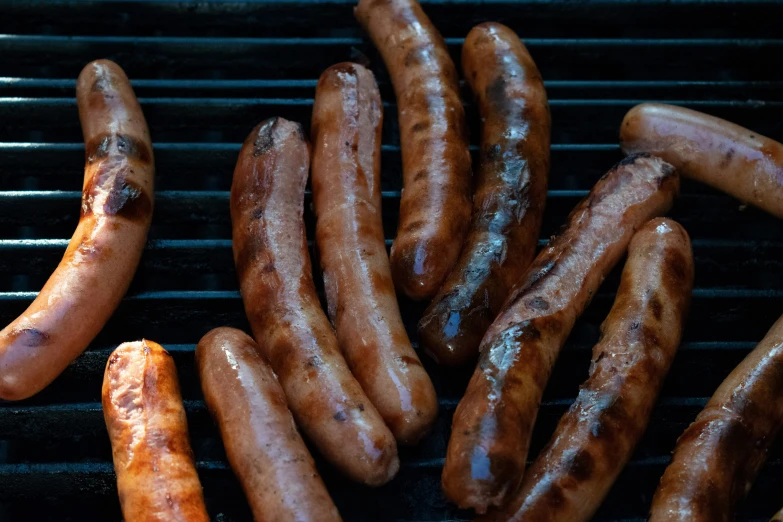 several  dogs and sausages are on the grill