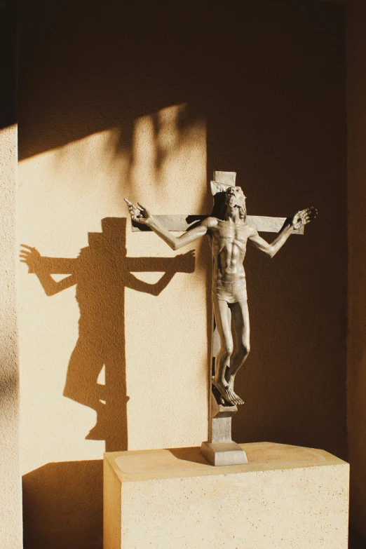 a sculpture with a cross and a shadow from the cross