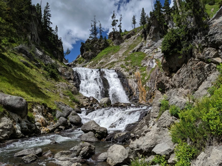 a large waterfall that is next to a green hillside