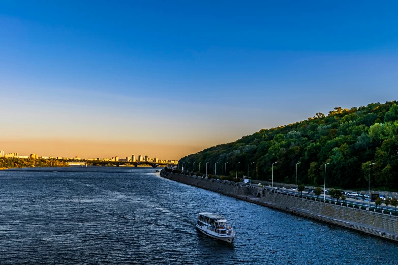 a boat floating down a river next to a large hill