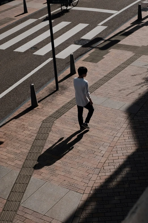 young man in casual clothes walking on the sidewalk with street signs